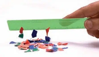 Charged plastic scale attracting small paper pieces